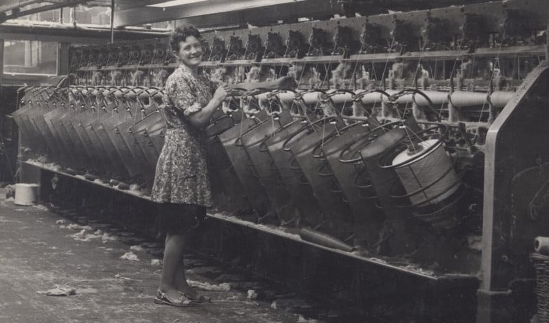 Archive photograph of a mill worker beside spinning frames