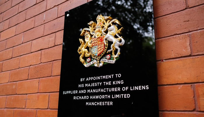 The Royal Warrant plaque on a brick wall: By Appointment to His Majesty The King, Supplier and Manufacturer of Linens, Richard Haworth Limited, Manchester